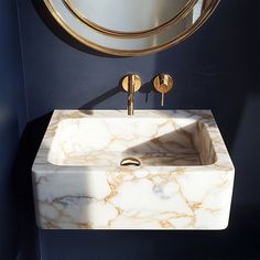 a white sink sitting under a mirror next to a wall mounted faucet in a bathroom