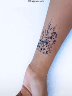 a woman's arm with a tattoo on it that has blue flowers and birds