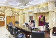 a woman sitting at a table in front of a large desk with chairs around it