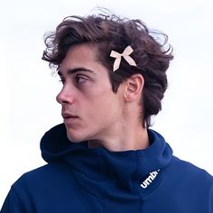 a young man wearing a blue hoodie with a pink bow in the middle of his hair