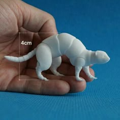 a hand holding a small white plastic animal