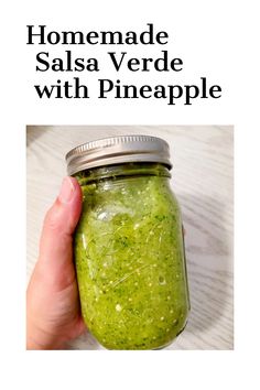 a hand holding a mason jar filled with homemade salsa verde and pineapple