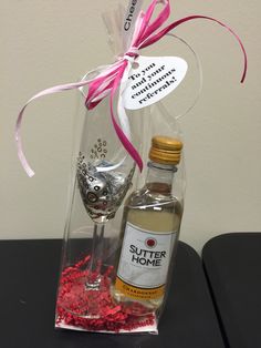 a bottle of liquor and some confetti in a glass with a pink ribbon