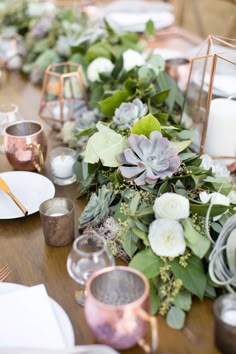 the table is set with candles, flowers and greenery for an elegant wedding reception