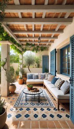 an outdoor living room with blue shutters and potted plants