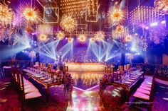 a banquet hall set up for a party with purple lighting and chandeliers hanging from the ceiling