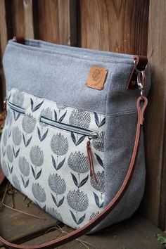 a gray and white bag sitting on top of a wooden fence