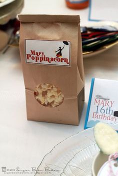 a bag of popcorn sitting on top of a table next to a plate and cup