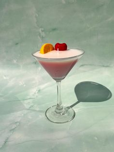 a martini glass filled with fruit on top of a table next to a white wall