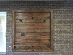 a brick wall with a wooden frame hanging on it's side in front of a window