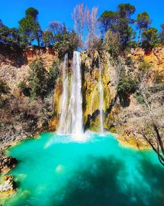 a waterfall with blue water and trees surrounding it