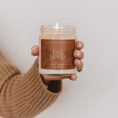 a woman holding a candle in her hands with the words fall leaves on it and an autumn theme