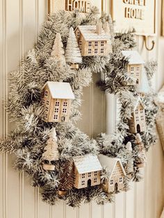 a wreath is hanging on the front door with small houses and fir trees around it