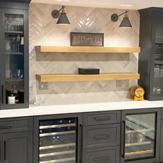 a kitchen with gray cabinets and white marble counter tops is pictured in this image, there are two wine racks on the wall