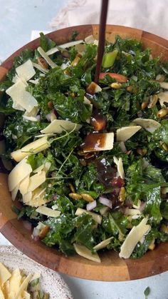 a wooden bowl filled with greens and cheese