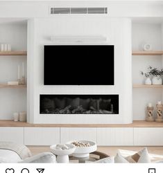 a living room with white furniture and a flat screen tv mounted on the wall above it