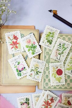 some stamps are laying on top of an old book with flowers and leaves painted on them