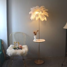 a lamp that is on top of a table next to a chair with a flower in it