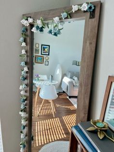 a mirror that has flowers on it in front of a table with chairs and pictures