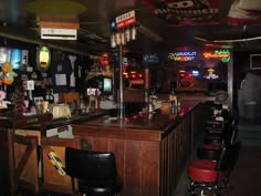 a bar with several stools and neon signs