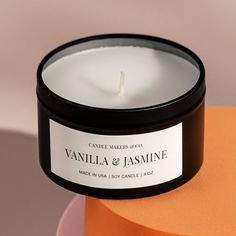 a candle sitting on top of a table next to an orange container with the label vanilla & jasmine