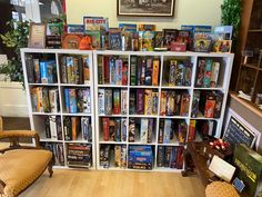 a bookshelf filled with lots of books in a living room next to a chair