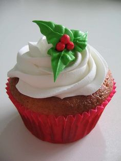 a cupcake with white frosting and holly decorations