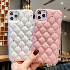 two pink and white iphone cases with gold studdings on them, one is holding the