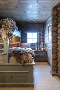 a bedroom with wooden walls and flooring has fur on the headboard, bedding, and pillows