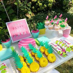 a table topped with pineapples and cupcakes