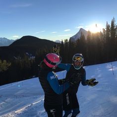 two people standing on top of a snow covered slope wearing skis and goggles