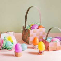 three baskets filled with colorful eggs sitting on top of a pink table next to each other