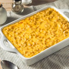 a casserole dish with cheese and meat in it sitting on a striped cloth