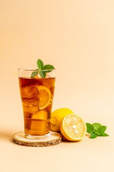 a glass cup filled with tea next to lemons and mint on a saucer