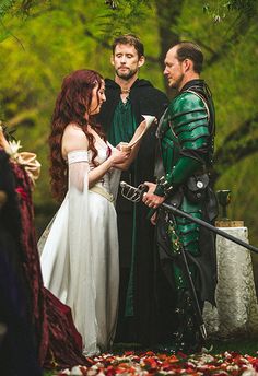 a man and woman dressed up in medieval costumes standing next to each other with swords