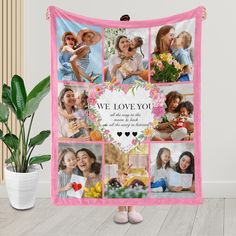 a woman holding a pink and white blanket with pictures of her family on it, in front of a potted plant