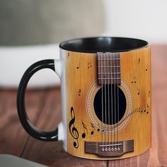 a wooden guitar mug with musical notes on the outside and inside, sitting on a table