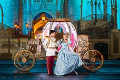 a man and woman dressed as disney characters in front of a horse drawn carriage at night