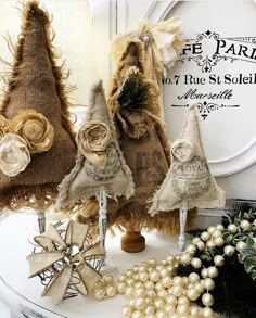 three burlap christmas trees are sitting on top of a table with ornaments around them