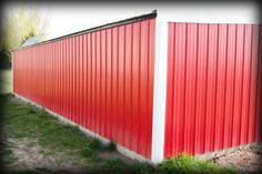 the side of a red metal building with green grass