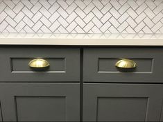 a gray cabinet with gold handles and knobs