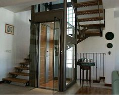 a spiral staircase in the middle of a living room with glass walls and wooden steps