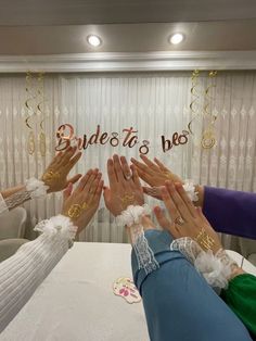 four people are holding their hands together at a table with the word bride to be written on it