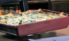 a casserole dish with spinach and cheese in it sitting on a table