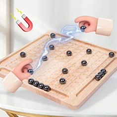 two hands are playing a board game with magnets and beads on the table next to each other