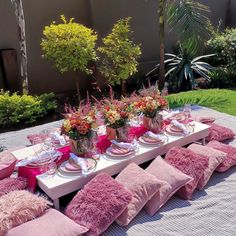 a table set up with pink pillows and flowers