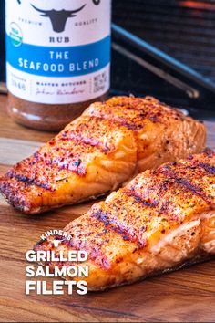 two grilled salmon fillets sit on a cutting board next to a bottle of seafood blend