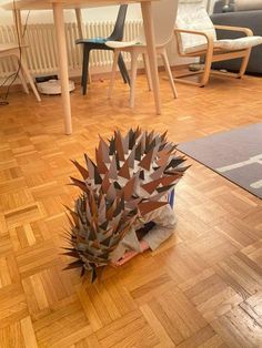 a paper sculpture sitting on top of a hard wood floor next to a dining room table