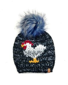 a knitted batman hat with blue fur pom