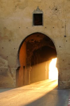 the sun is shining through an arch in a stone building with light coming from it